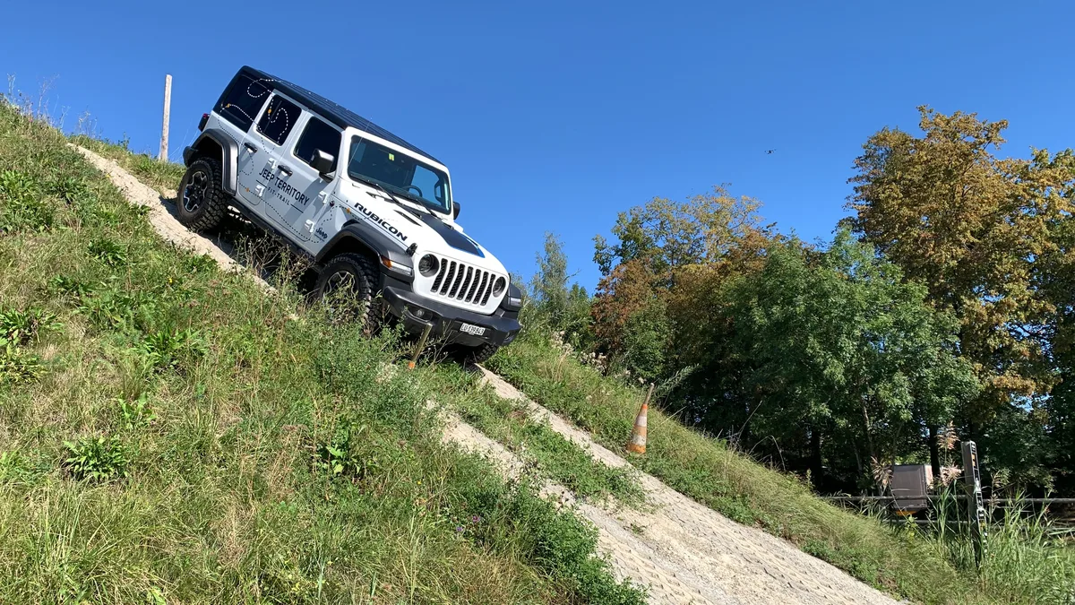 Ein Jeep fährt eine steile Strasse hinunter. 