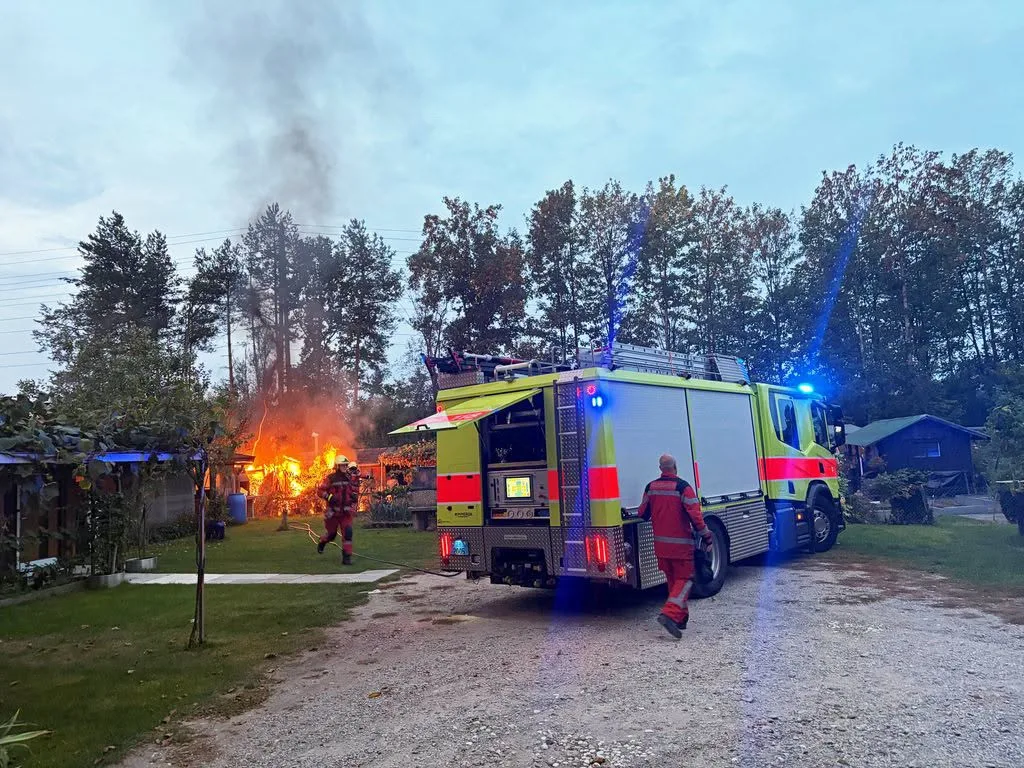 Die Feuerwehr konnte das Feuer schnell löschen. Feuer, Feuerwehrleute und ein brennendes Gartenhäuschen