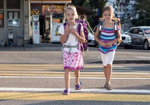 21296153-3 Schulanfang 2012: Tausende Kinder erleben am 20. August 2012 ihren ersten Schultag; hier marschieren zwei ABC-Schützinnen aus Grüningen über den Fussgängerstreifen, um zum Schulhaus zu gelangen.