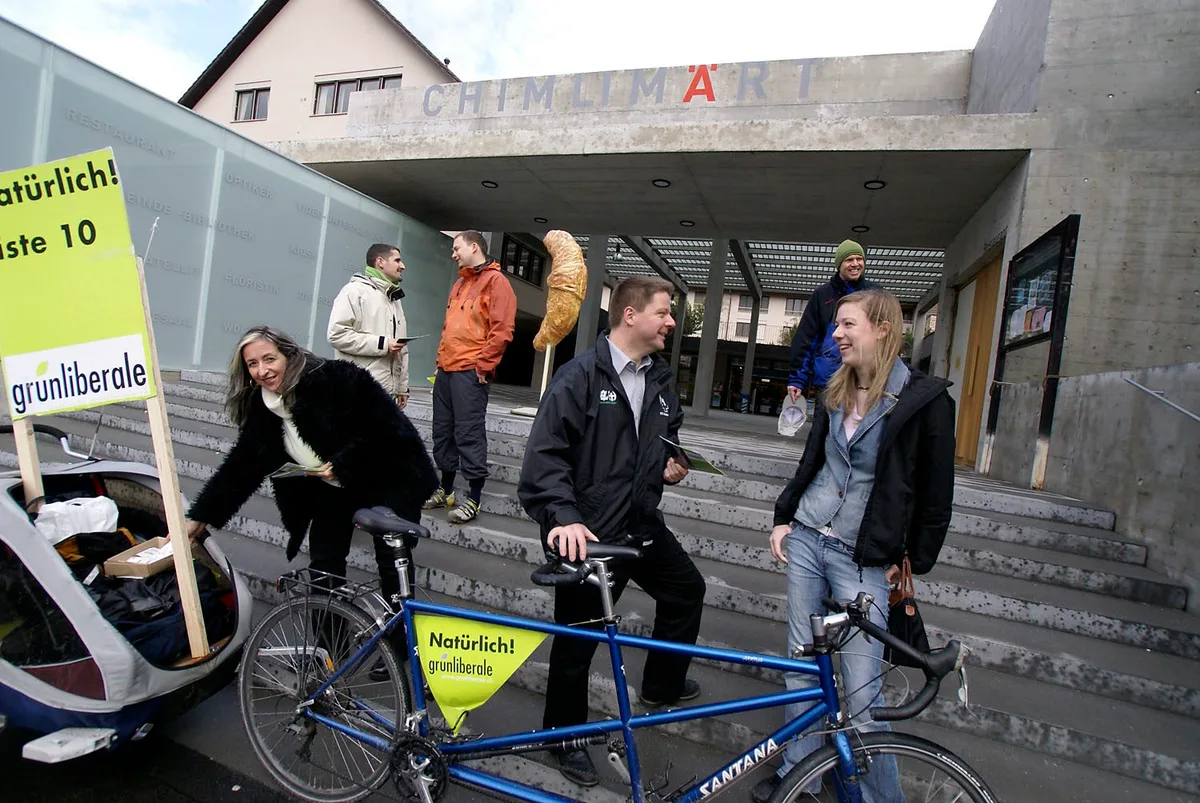 Ein Gruppe von Menschen betreibt Wahlkampf vor einem Einkaufszentrum. 