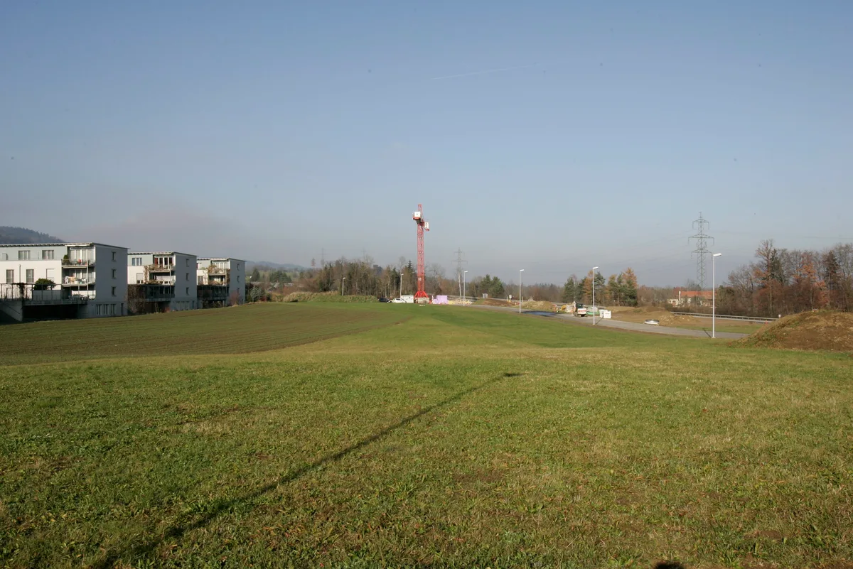 Bauland Längi-Hanselmaa in der Gemeinde Egg: grüne Wiese, Autobahn und Wohnsiedlung.