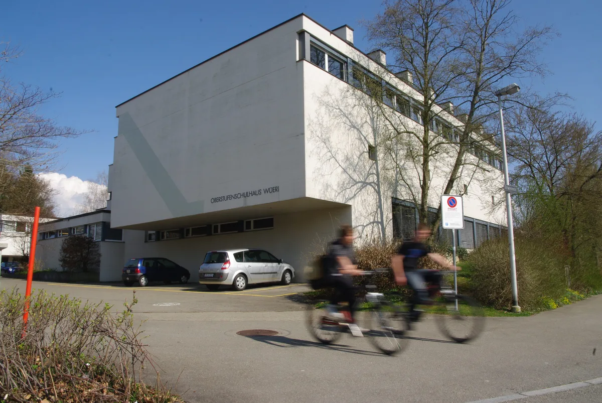 Zwei Velofahrer fahren beim Schulhaus Wüeri vorbei.