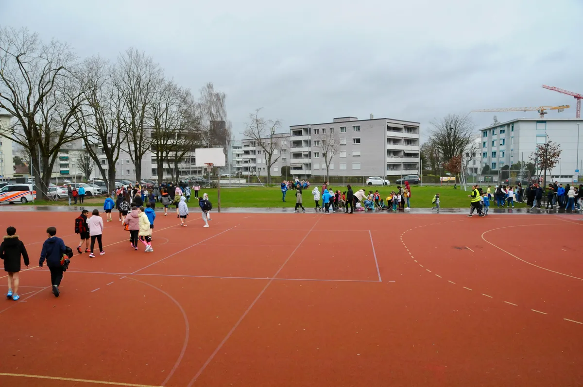 Man sieht Kinder und Lehrpersonen zum Sammelplatz strömen.