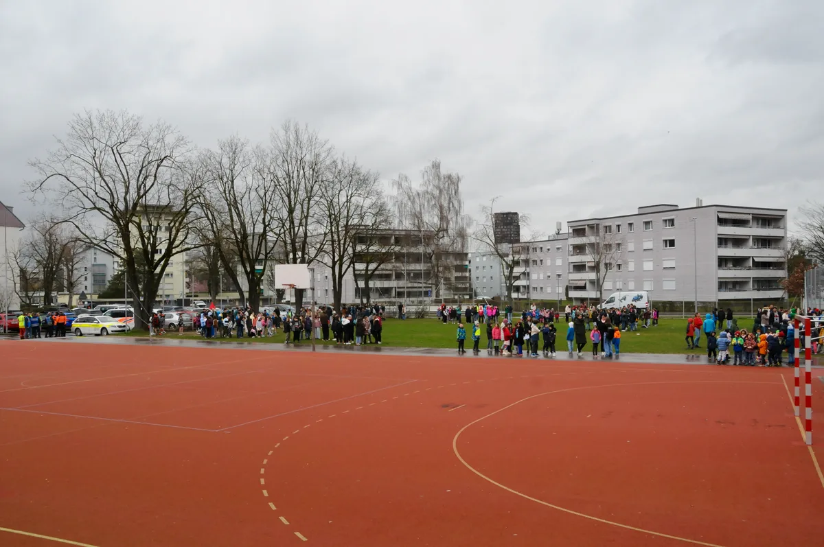 Man sieht Schüler und Lehrpersonen auf dem Evakuierungsplatz.