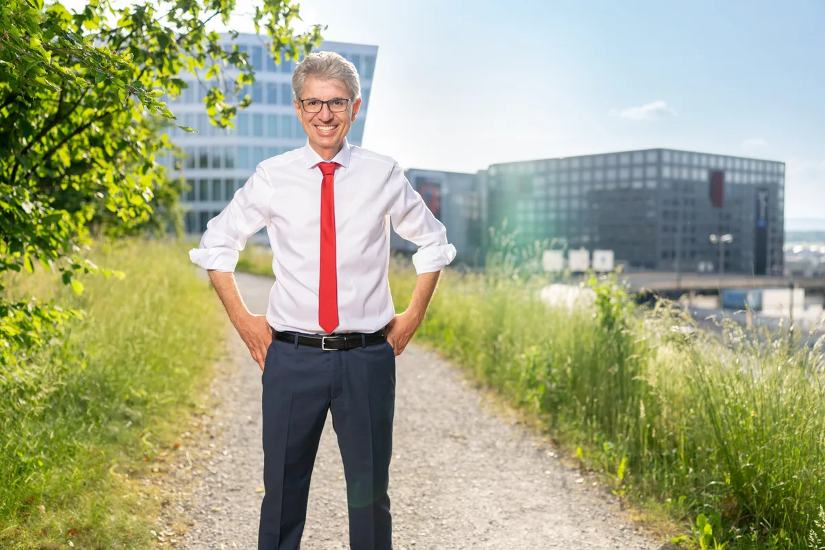 Teurer Hüsli-Traum in Pfäffikon: Donato Scognamiglio rät Eigenheimbesitzern, nicht nur in die Immobilie, sondern auch in die Beziehung zu investieren. Ein Mann in weissem Hemd mit roter Krawatte steht auf einem Kiesweg.