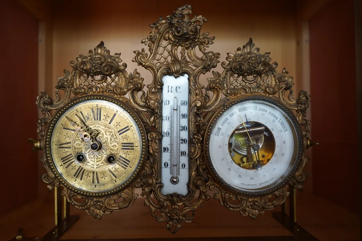 Eine antike Uhr mit Thermometer und Barometer.