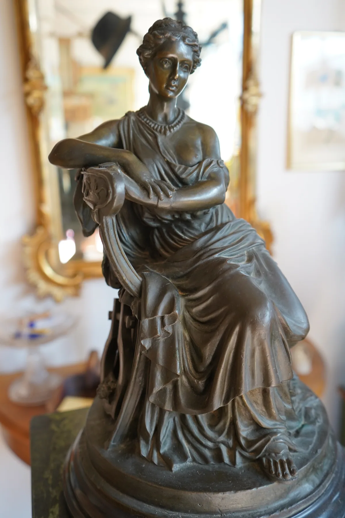 Bronzefigur einer sitzenden Frau.