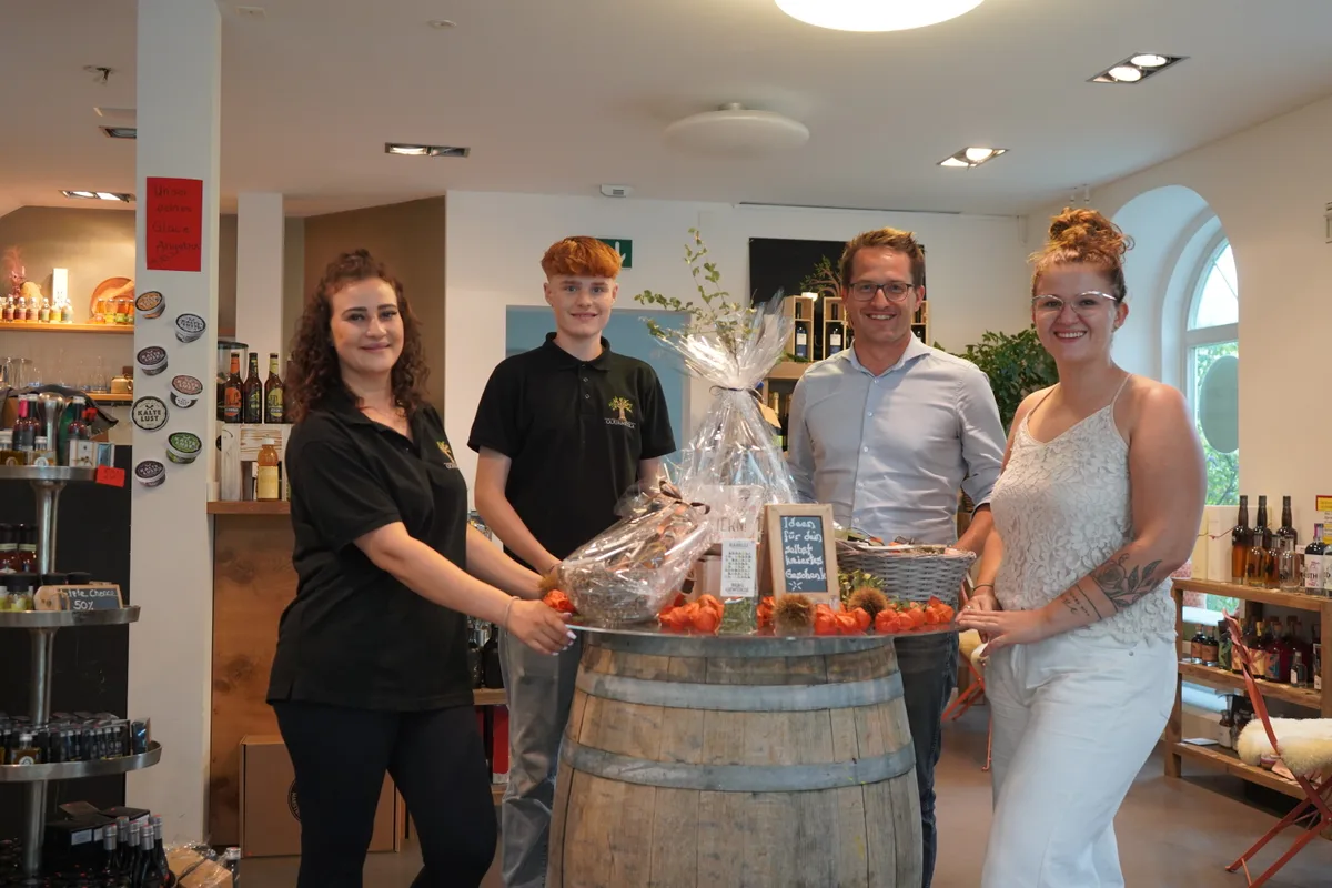 Vier Menschen stehen in einem Ladenlokal um einen runden Tisch.