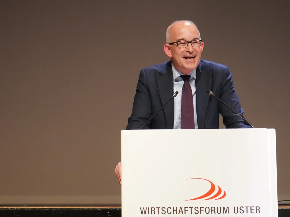 Ein Mann mit Glatze und Brille steht auf einer Bühne hinter einem Rednerpult mit der Aufschrift «Wirtschaftsforum Uster».