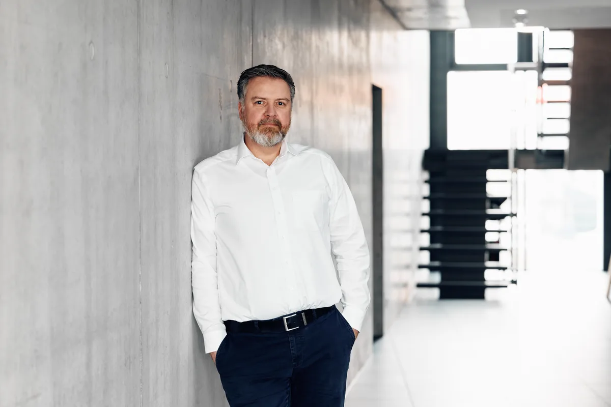 Der deutsche Industrielle Felix Reichardt ist neuer Besitzer der Schweizer Traditionsfirma Stewi. Ein Mann mit Bart in weissem, offenem Hemd lehnt an eine Wand.