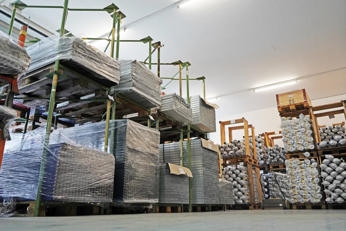 Blick in das gut gefüllte Warenlager von Stewi. Man sieht in durchsichtigen Plastikfolien verpackte Wäschespinnen.,
