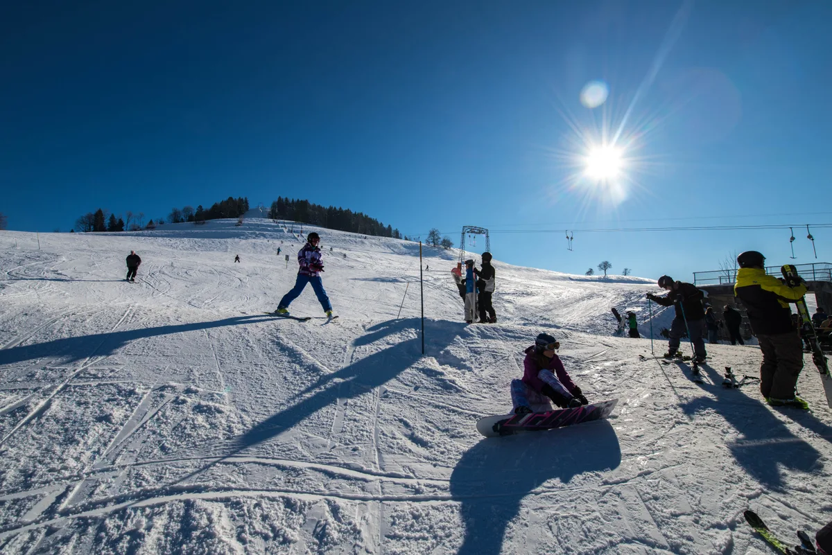 Skifahrer bei Sonnenschein auf einer Piste.