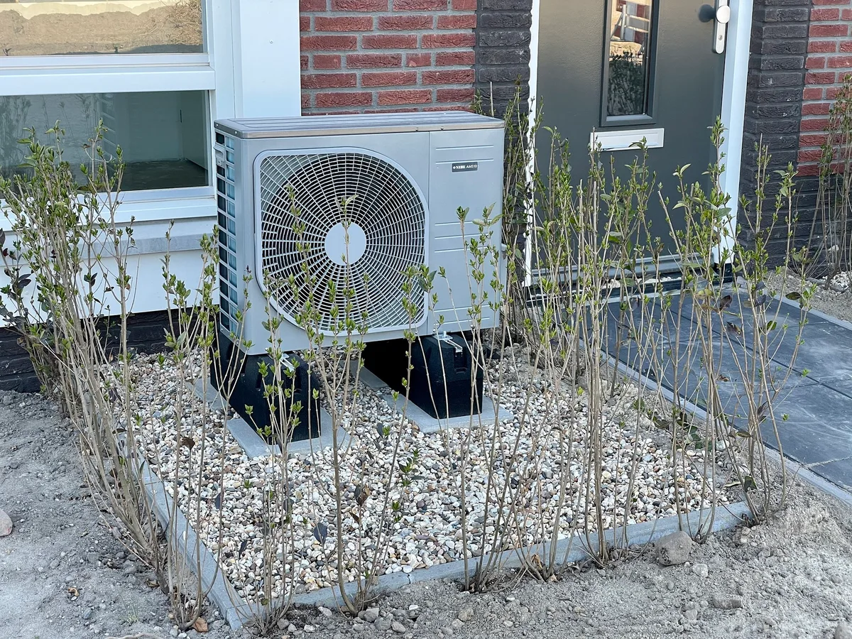 Eine Luft-Wasser-Wärmepumpe vor einem Haus.