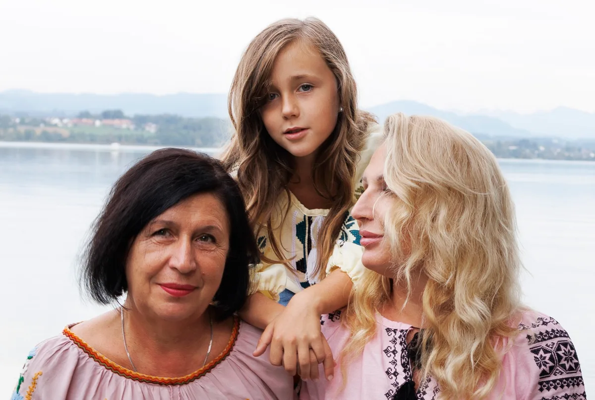 Drei Frauen unterschiedlichen Alters auf einem Bild, im Hintergrund ein See. 