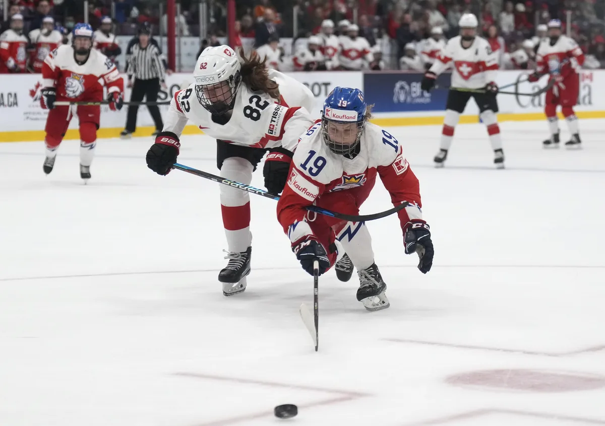 Czechia forward Natalie Mlynkova (19) battles for the puck against Switzerland defender Alessia Baechler (82) during the second period of the bronze medal IIHF Women's World Hockey championship game in Brampton, Ontario, on Sunday, April 16, 2023. (Nathan Denette/The Canadian Press via AP)