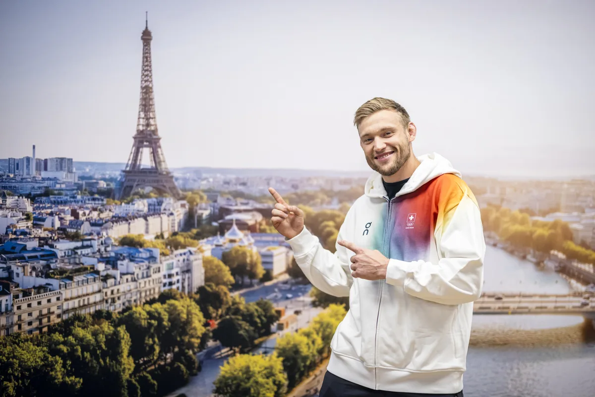Nils Stump, Judo Athlet, posiert waehrend der Kleiderabgabe ihre Kleider fuer die Olympischen Spiele 2024 in Paris vor einem Poster mit einem Bild des Eiffenlturms, am Montag, 8. Juli 2024 in Dieitikon.  (KEYSTONE/Michael Buholzer)