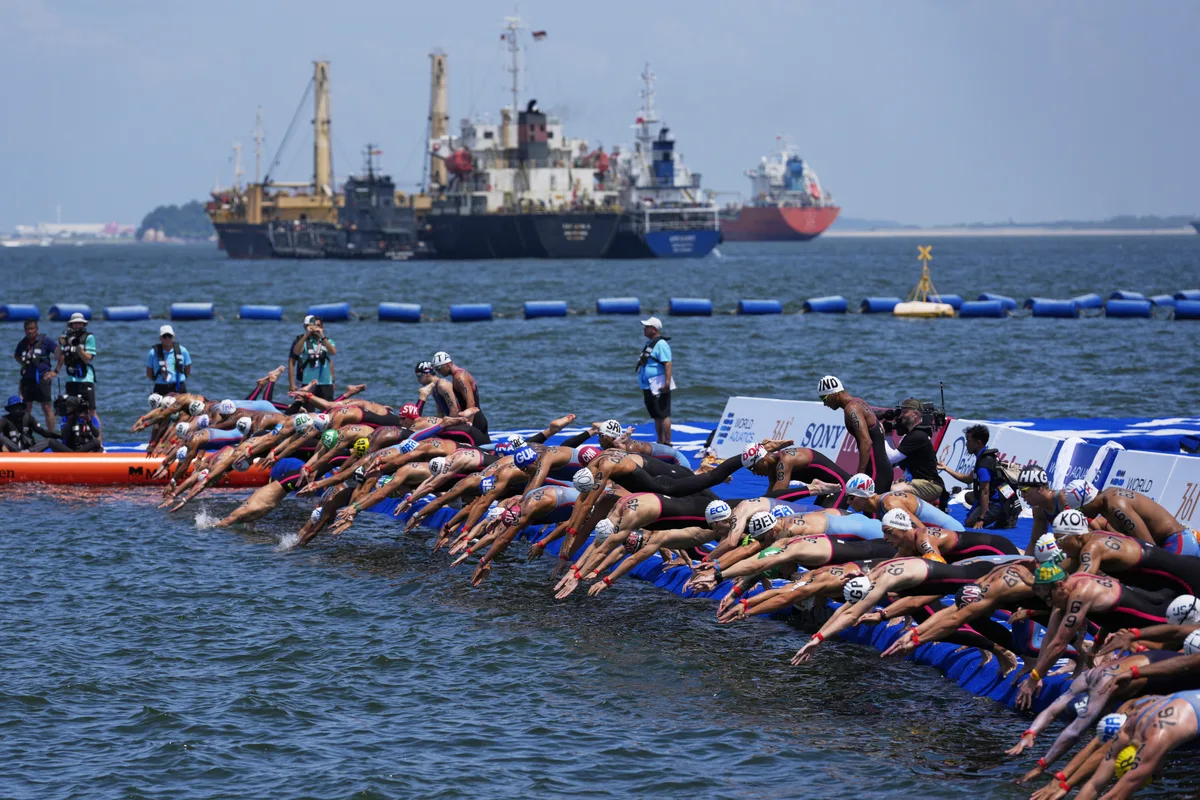 Swimmers dive in at the start of the men's 10km open water swim at the world swimming championships in Singapore, Wednesday, July 16, 2025. (AP Photo/Vincent Thian)