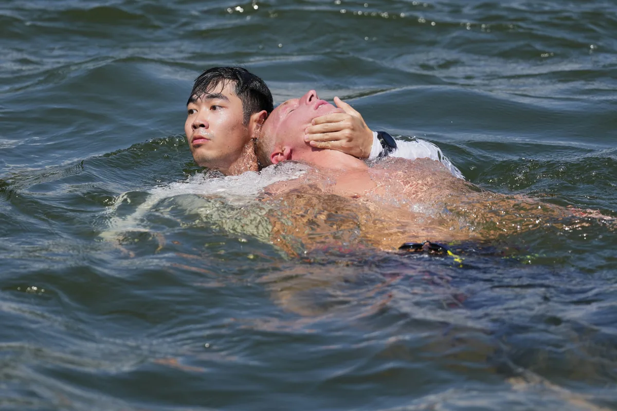 Marc-Antoine Olivier of France is assisted back to shore by a life guard while competing in the men's 10km open water swim at the world swimming championships in Singapore, Wednesday, July 16, 2025. (AP Photo/Vincent Thian)
Singapore Swimming Worlds