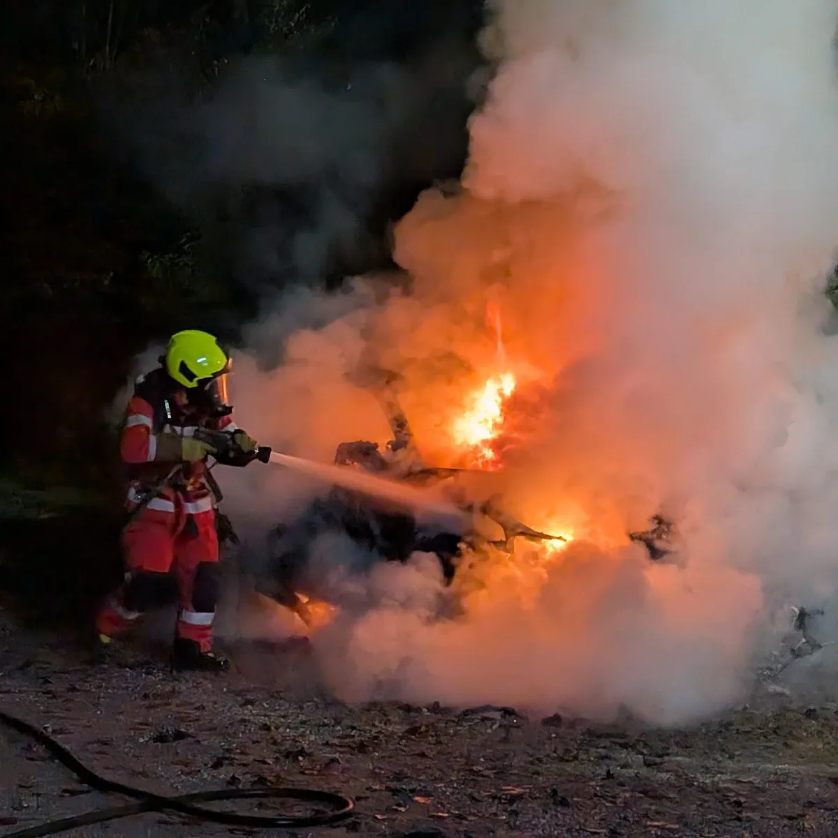 Ein Feuerwehrmann beim löschen des Autos.
