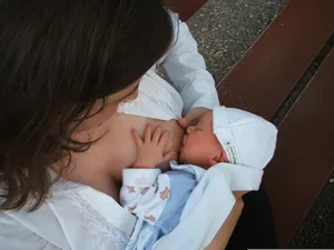 25467232-3 eine Frau auf einer Bank stillt ihr Baby