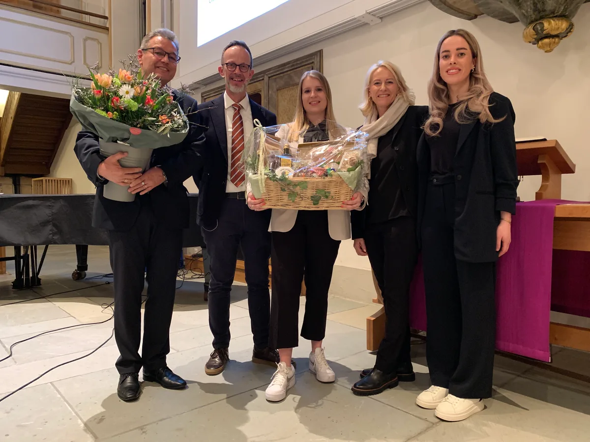 Fünf Leute mit Blumen und einem Früchtekorb stehen in der Kirche. 