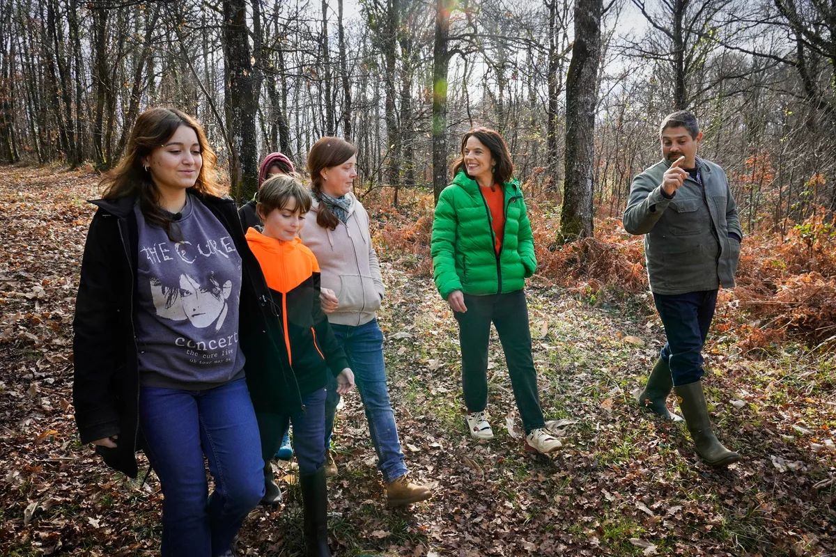 Moderatorin Mona Vetsch hat die Auswanderer in ihrem neuen Zuhause besucht. Man sieht Kinder und zwei Erwachsene bei einem Spaziergang im Wald.