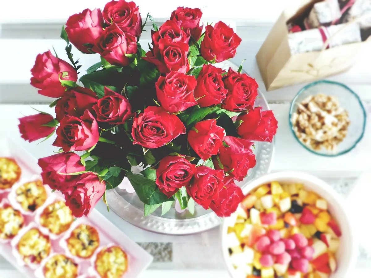 Ein Blumenstrauss mit Rosen auf einem gedeckten Brunch-Tisch.