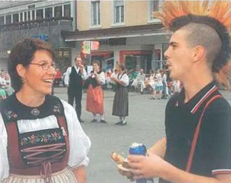 Eine Frau in Appenzellertracht und ein Mann mit Irokese-Frisur sprechen miteinander.