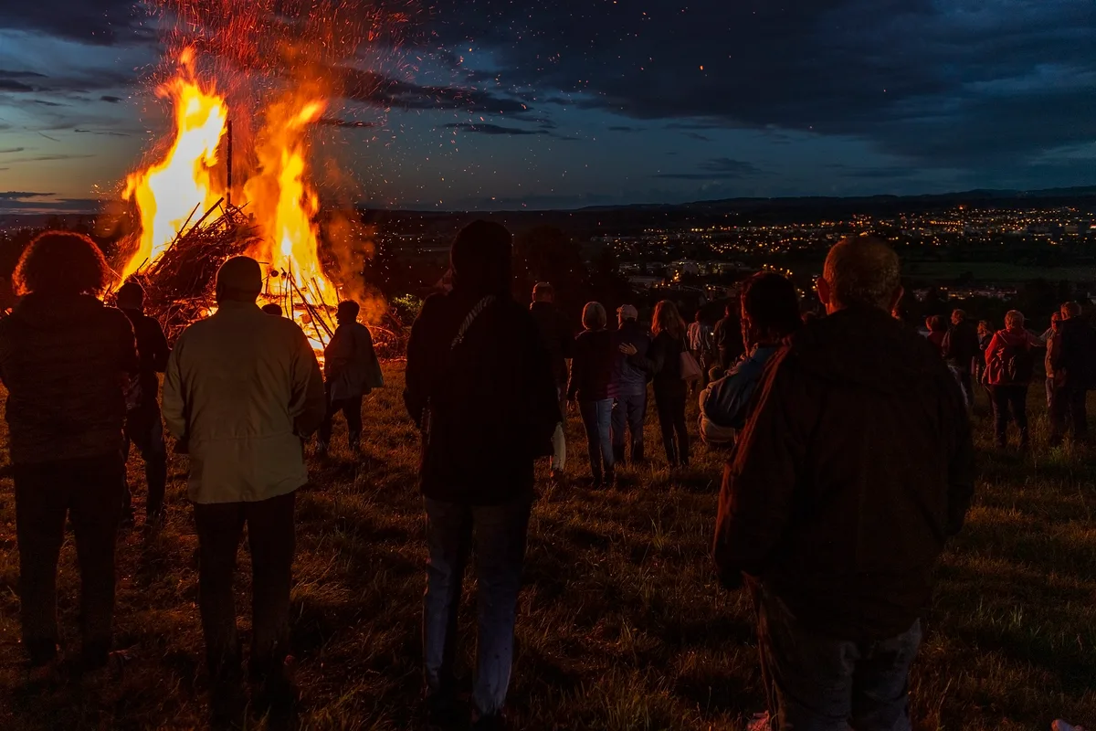 Leute stehen um ein grosses Feuer.
