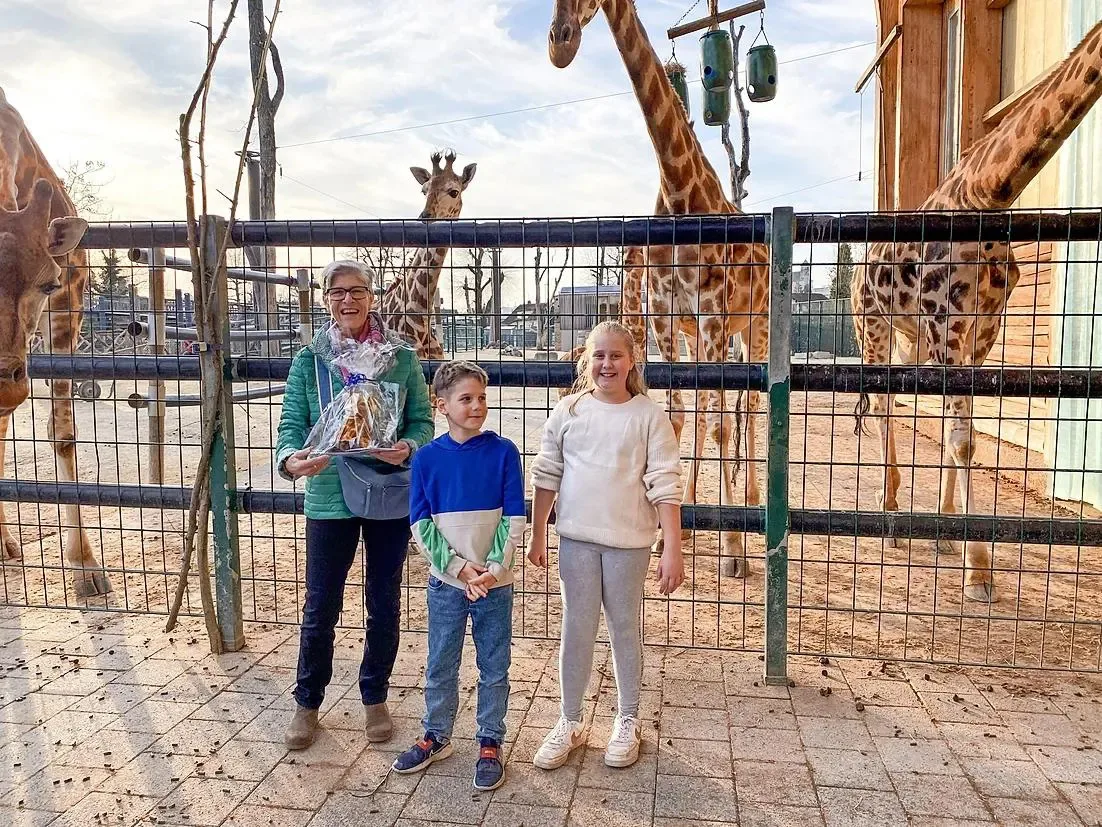 Grossmutter mit zwei Enkelkindern vor dem Giraffengehege im Zoo.