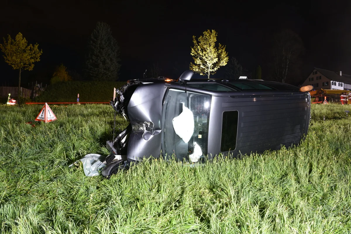 Ein graues Fahrzeug liegt auf der Seite auf einer Wiese. Ein graues Fahrzeug liegt auf der Seite auf einer Wiese.