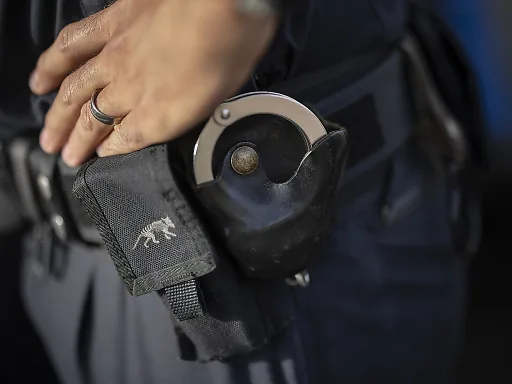 Ein Polizist greift sich in die Huefte. Ein Polizist greift sich in die Huefte.