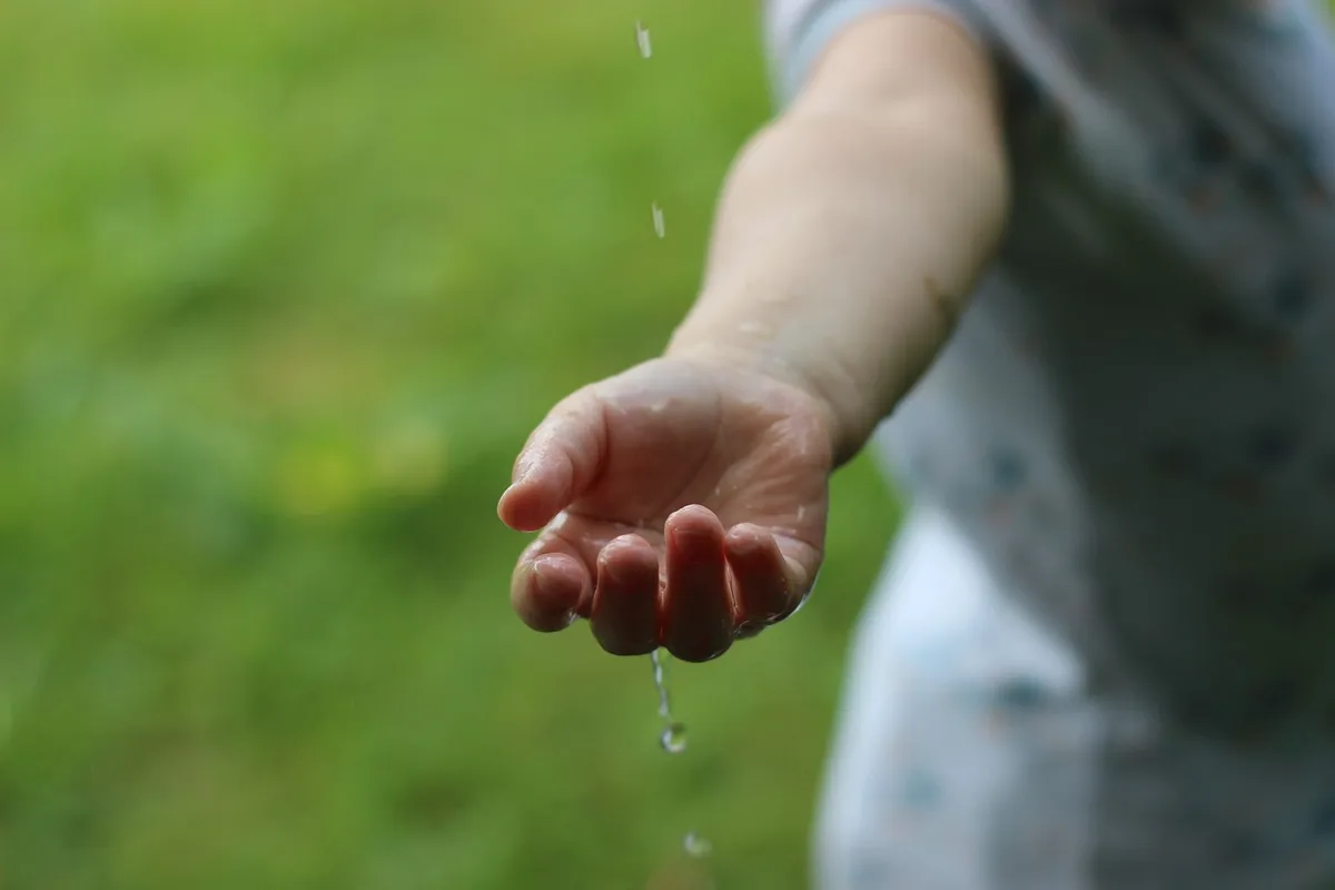 Eine Kinderhand im Regen.